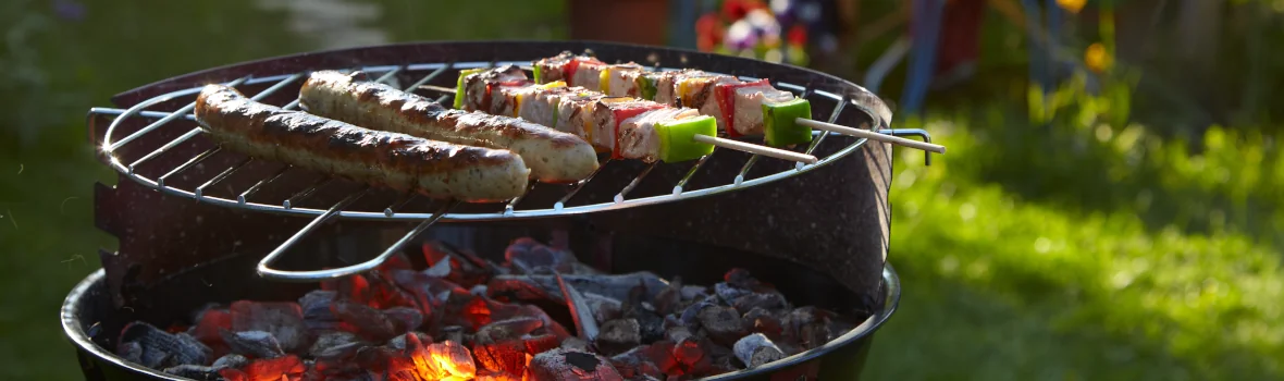 runder Holzkohlegrill mit Fleisch und Gemüse drauf