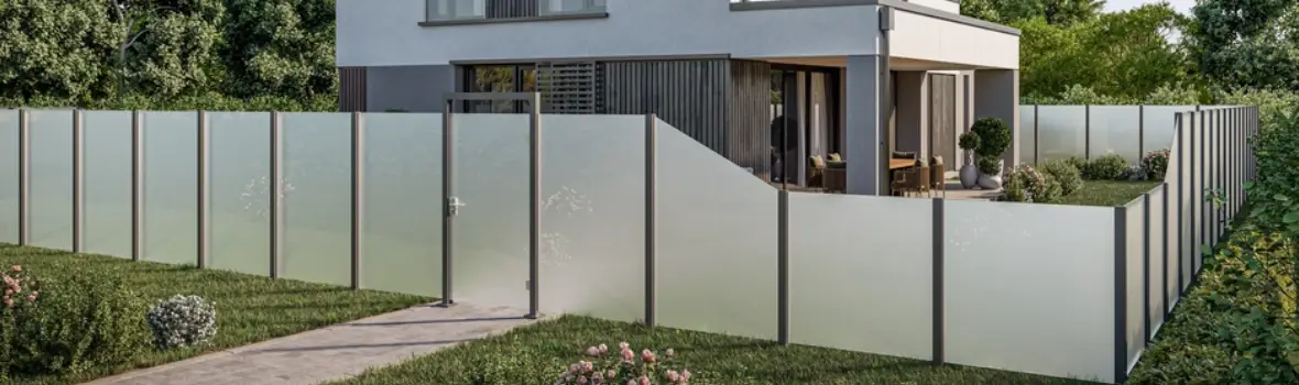 Ein Glaszaun begrenzt den Garten eines Hauses.