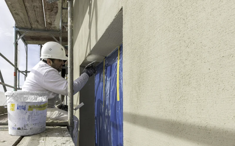 Handwerker bringt Mörtel auf Außenfassade an