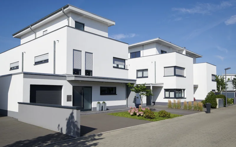modernes weißes Haus mit Flachdach, Garage und kleiner Grünfläche