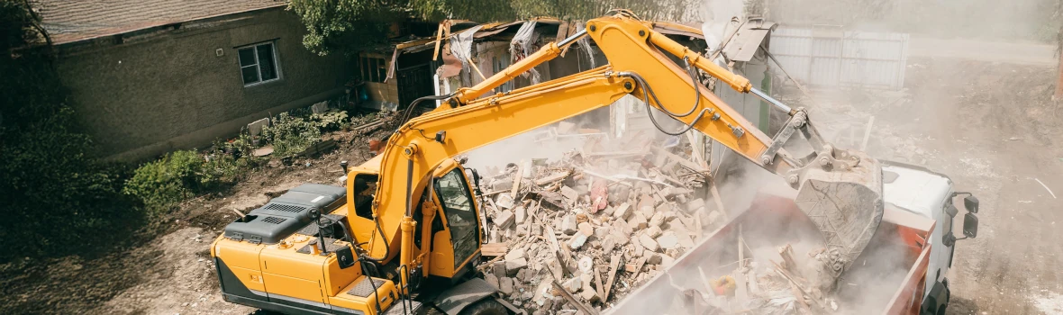 Ein Bagger, der Bauschutt in die Ladefläche eines LKW's kippt.