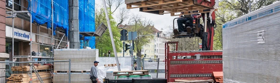 Baustelle mit Kränen, Baumaterialien und Baustellenfahrzeugen auf einer Straße 