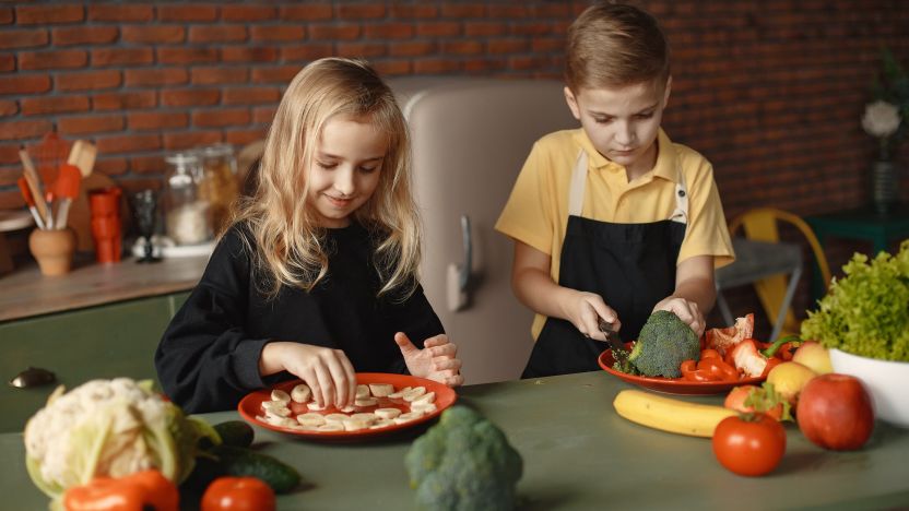2 children chopping vegetables in a kitchen