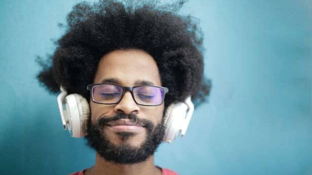 Man in red crew neck shirt with glasses wearing headphones