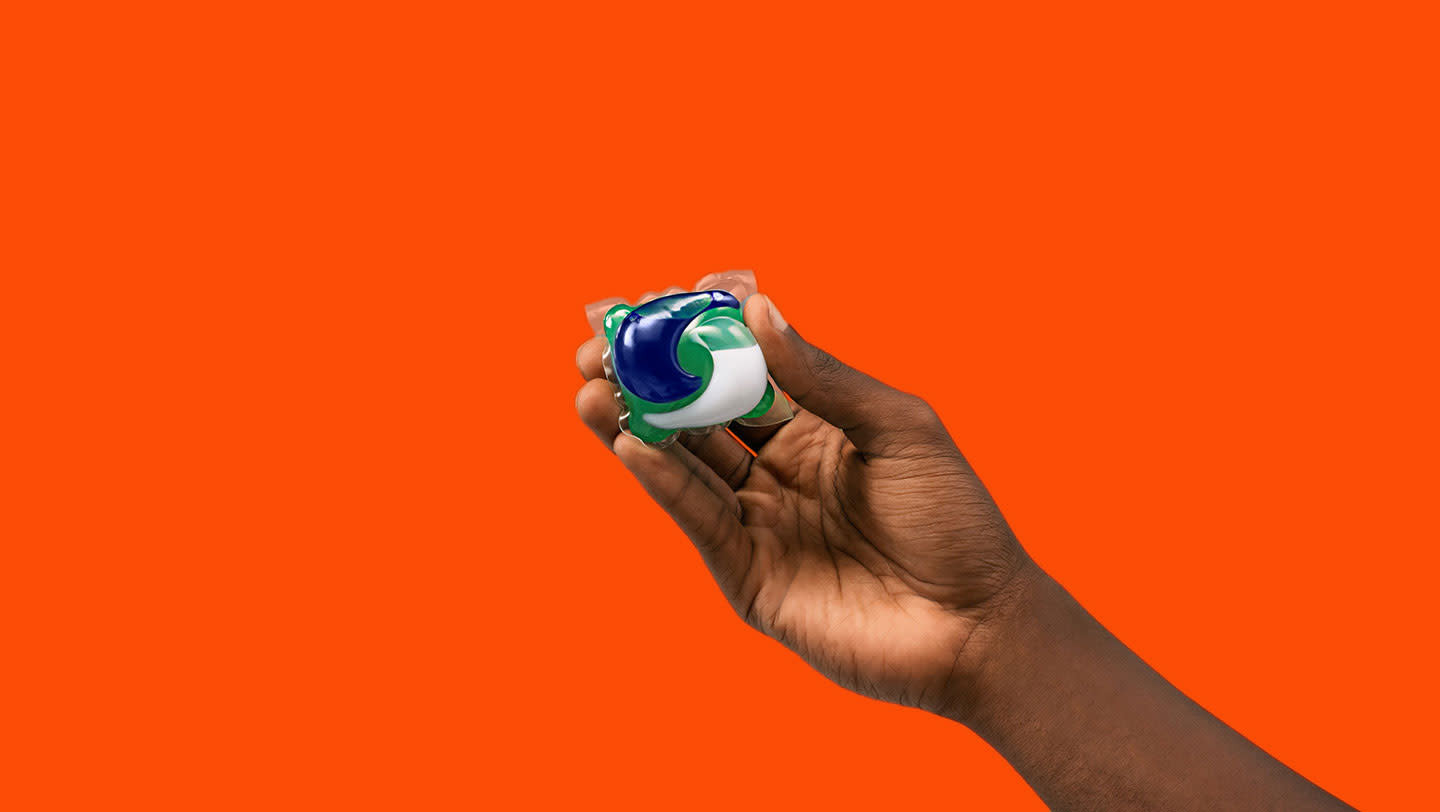 A person holding one Tide PODS washing capsule