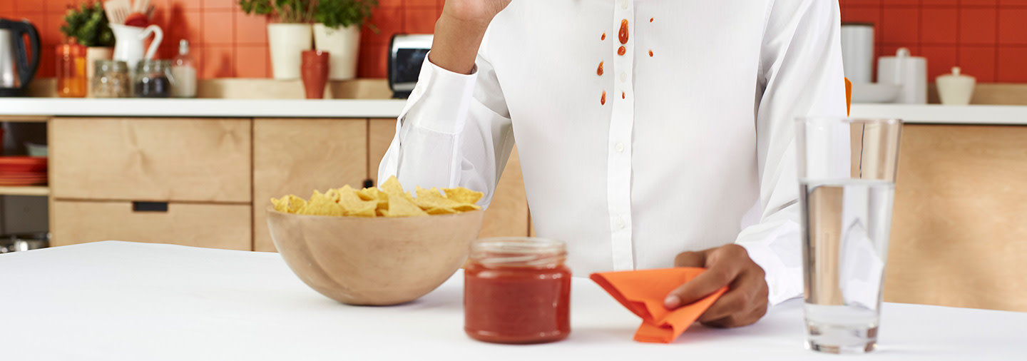 A person wearing a white shirt stained with salsa sauce