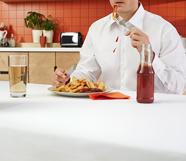 A person wearing a white shirt stained with ketchup