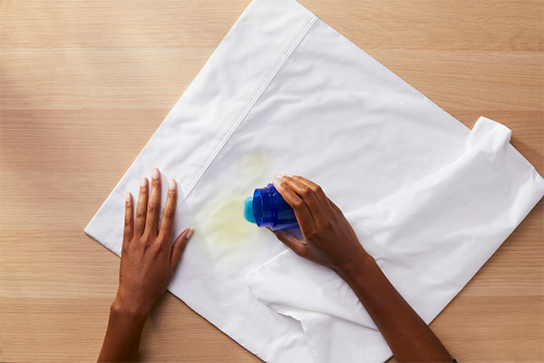 A person pouring Tide liquid detergent onto the stain