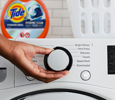 A person selecting the wash cycle on a washing machine