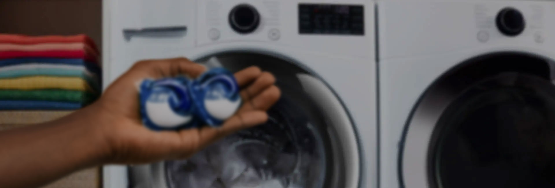 A person holding a Tide liquid detergent product in front of a washer