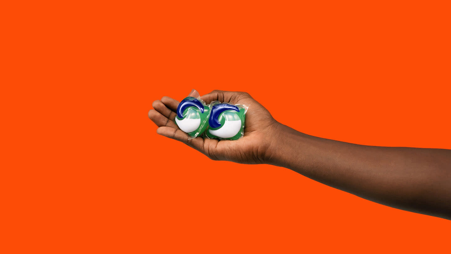 A person holding 2 Tide PODS washing capsules
