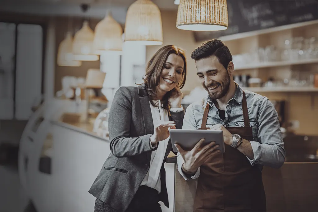 Barista masculin et femme faisant défiler des données sur une tablette.