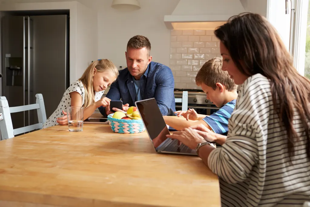 HLN.be op desktop en mobiel, vrouw leest aan tafel op de laptop en man op de mobiele telefoon