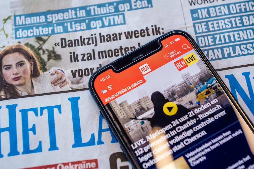 Man houdt mobiele telefoon vast waarop hij hln.be leest