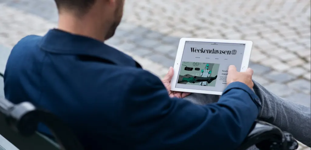 Man leest Weekendavisen op een bankje