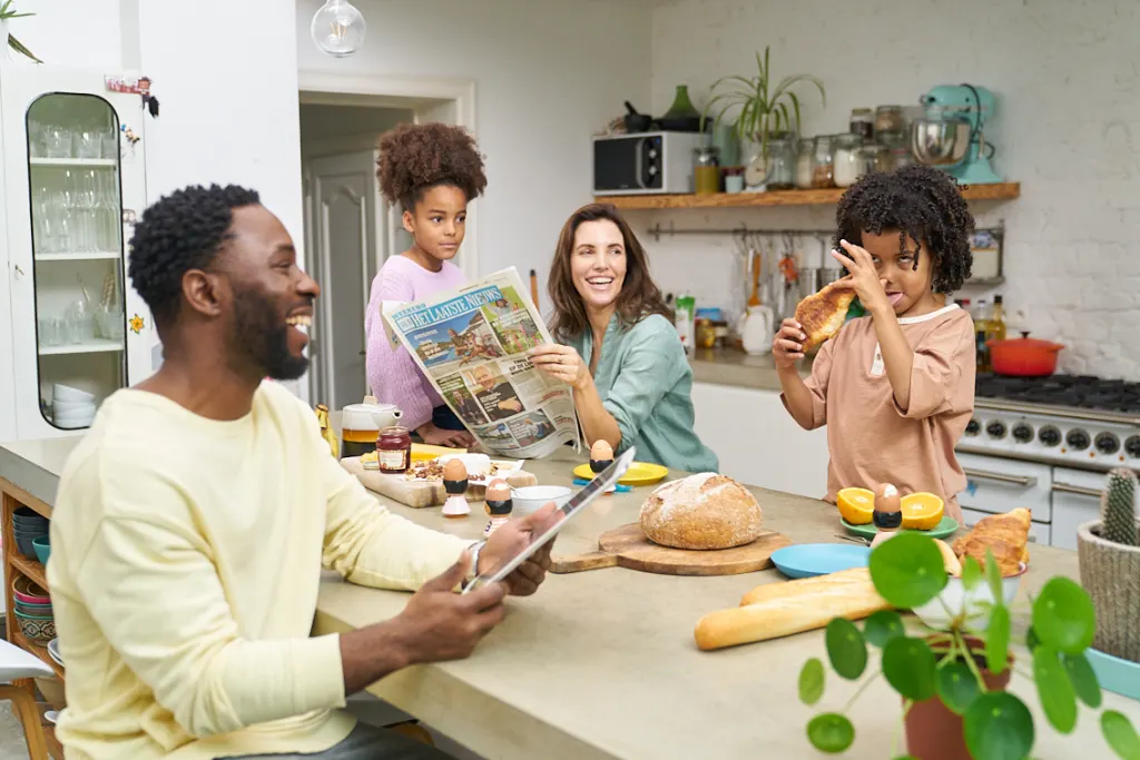 Famille de 4 personnes lit Het Laatste Nieuws pendant le petit-déjeuner