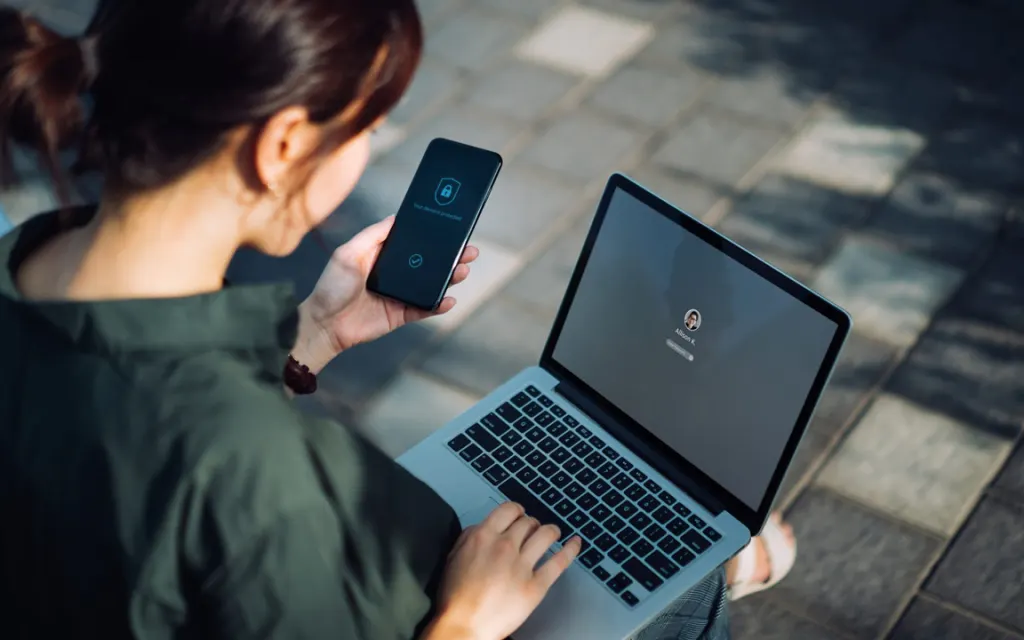 Vrouw met gsm in de hand logt in op haar laptop