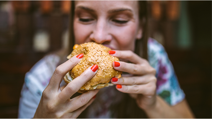 Woman taking bite of cheeseburger