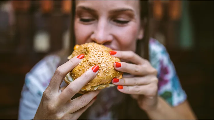Woman taking bite of cheeseburger