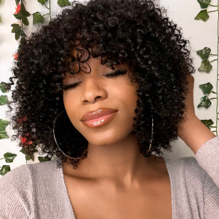 A beautiful black female wearing Mayvenn's Natural Black Curly Bob Wig with Bangs, a mid to the shoulders natural looking curly wig.