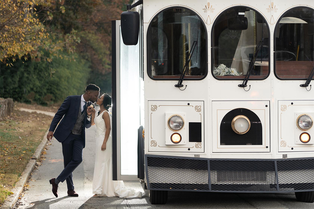 Bride and groom kissing outside of their wedding trolley