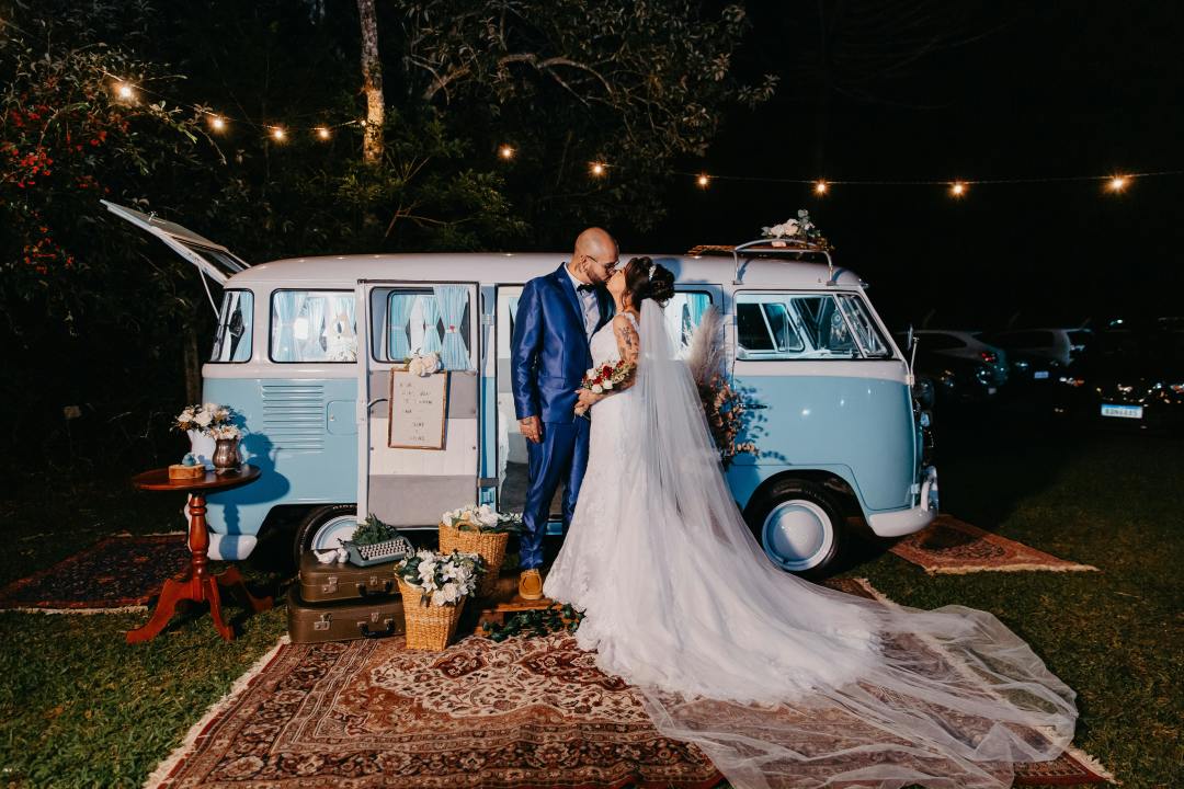 Bride and groom at night outside of a decorated VW blue bus