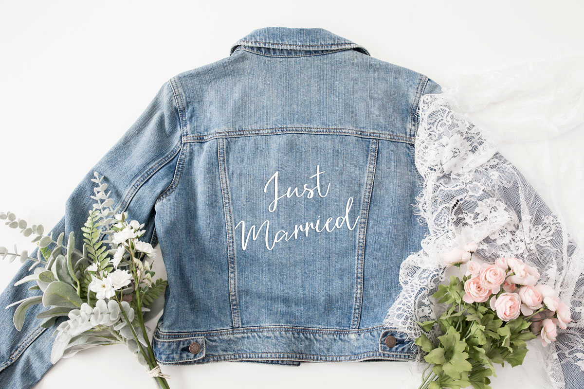 "Just Married" printed on the back of a jean jacket with lace and florals.