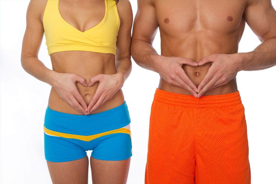 Une femme et un homme debout, formant un cœur avec leurs mains