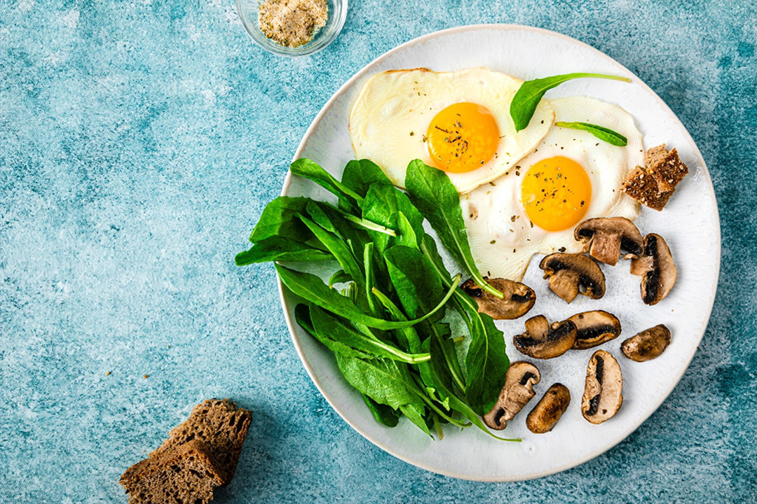 Une assiette d'œufs, de légumes et de champignons sur une table