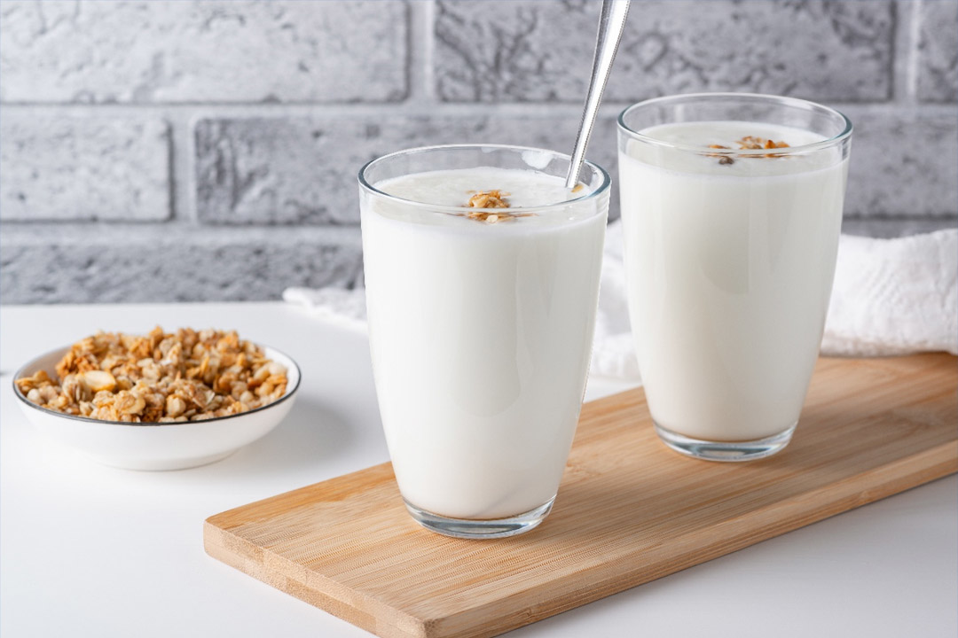 Deux verres de lait et un bol de céréales sur une table