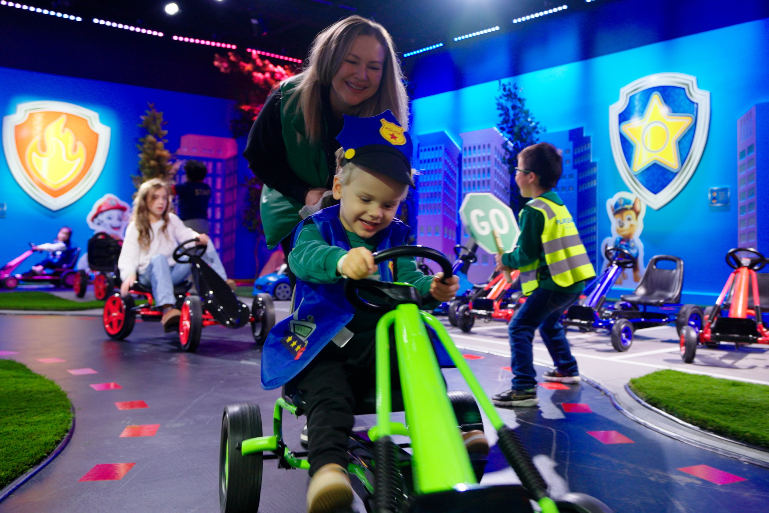Looking for things to do as a family in Atlanta? Explore The Paw Patrol Experience Only at CAMP in Atlanta. Image is a kid driving a ride on toy in a Paw Patrol costume on a race track. 