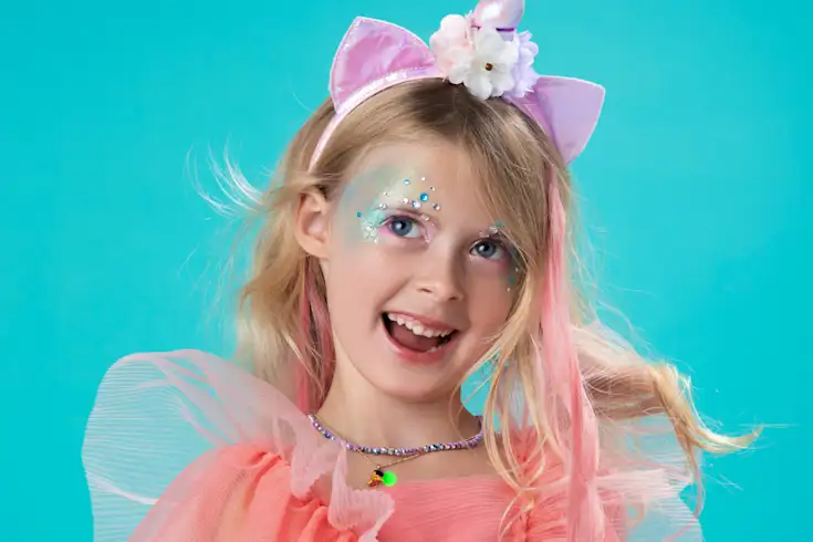 Kid with sparkly face paint and a unicorn headband