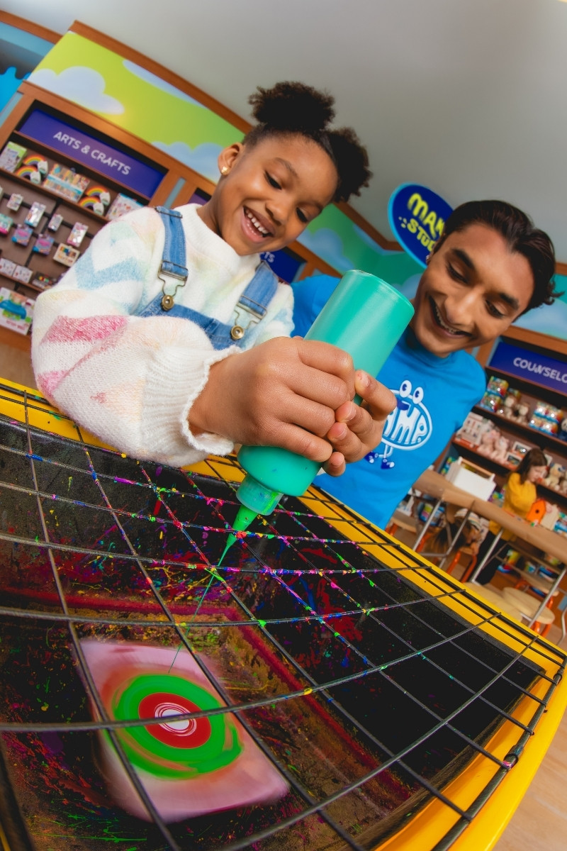Child making spin art with CAMP Counselor at CAMP Maker Studio