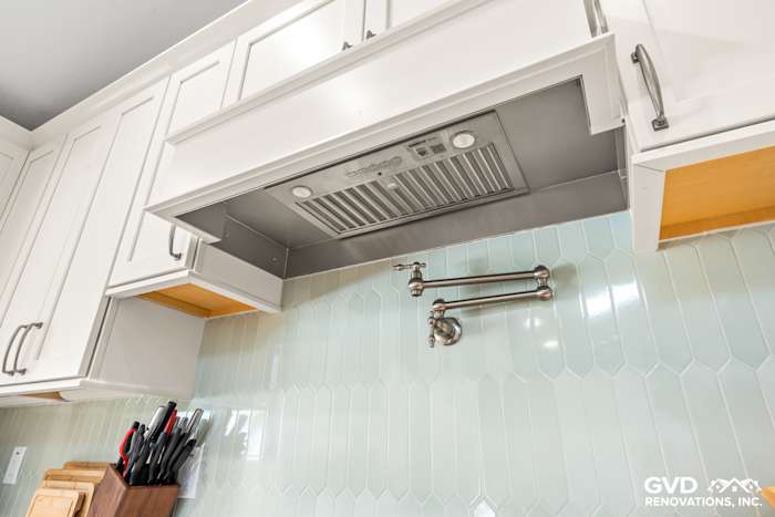 Custom kitchen range hood and teal hexagon backsplash in remodeled Carmichael kitchen