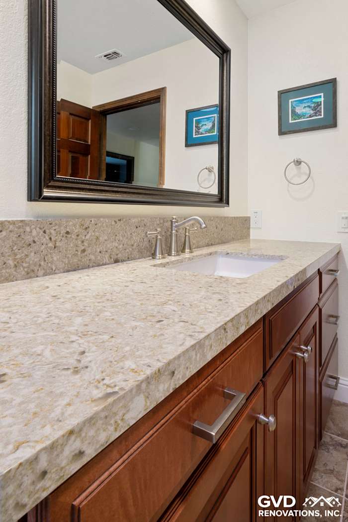 Elegant bathroom renovation featuring a granite countertop, dark wood cabinetry, and modern faucet in Fair Oaks