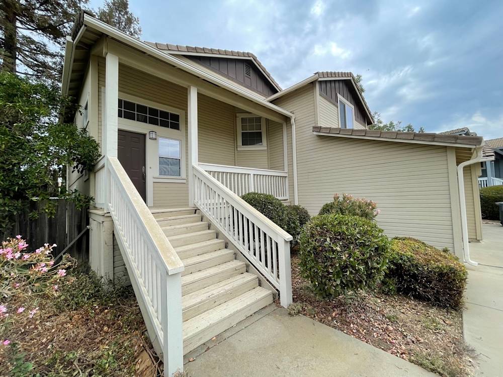 Exteriors of a Sacramento home featuring beige siding, stairs, and landscaped front yard