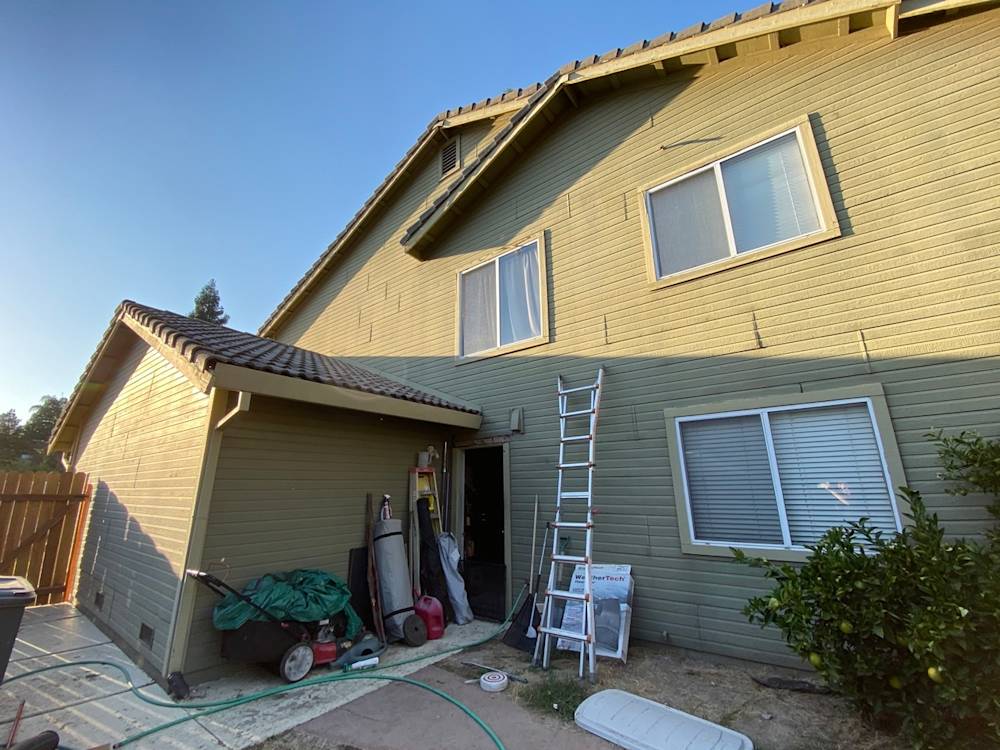Multi-story home in Sacramento with green siding and tools outside, ready for remodeling renovations