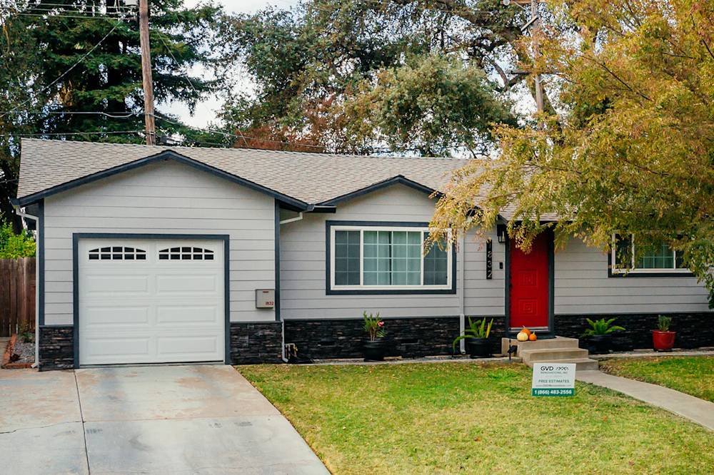 Modernized home exterior with gray siding, red door, and stone accents