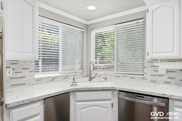 Bright kitchen corner featuring white cabinetry, quartz countertops, stainless steel sink, and modern subway tile backsplash