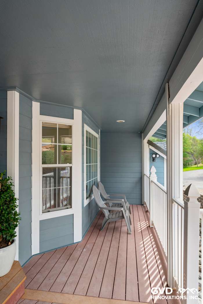 Covered porch featuring new blue James Hardie siding, wooden floors, and two outdoor chairs in Shingle Springs