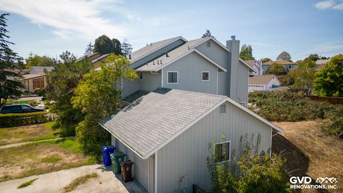 Updated home exterior in El Sobrante with new light gray siding and Milgard windows, surrounded by landscaping