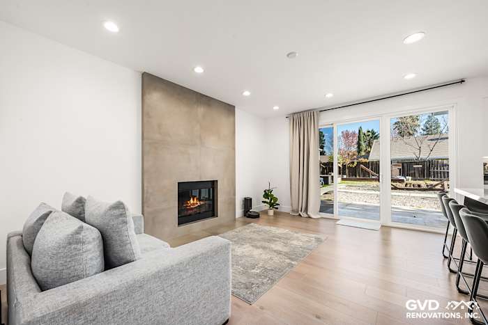 Modern living room in Antelope with sleek fireplace, hardwood flooring, large windows, and soft gray couch