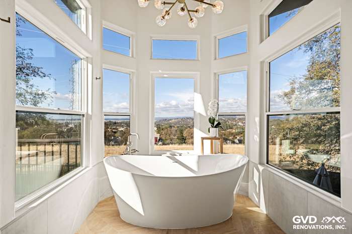Freestanding BainUltra air jet tub near large windows, custom tile flooring, and scenic views in El Dorado Hills bathroom