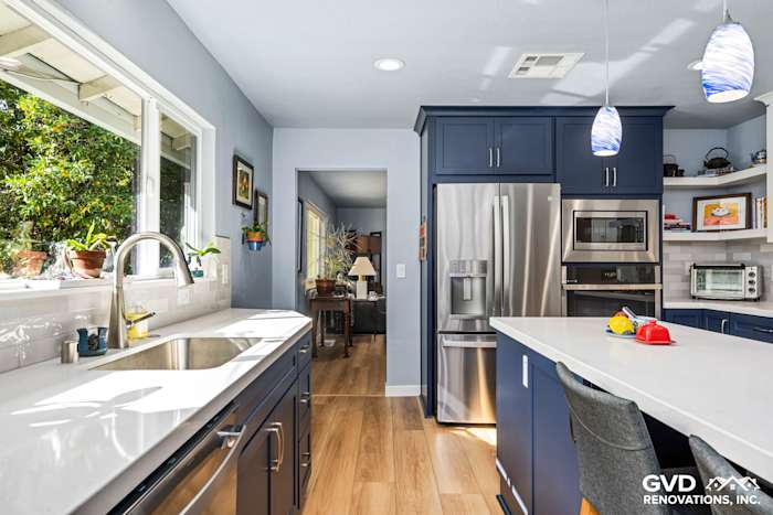 Bright kitchen with navy blue cabinetry, stainless steel appliances, and a large island with a quartz countertop