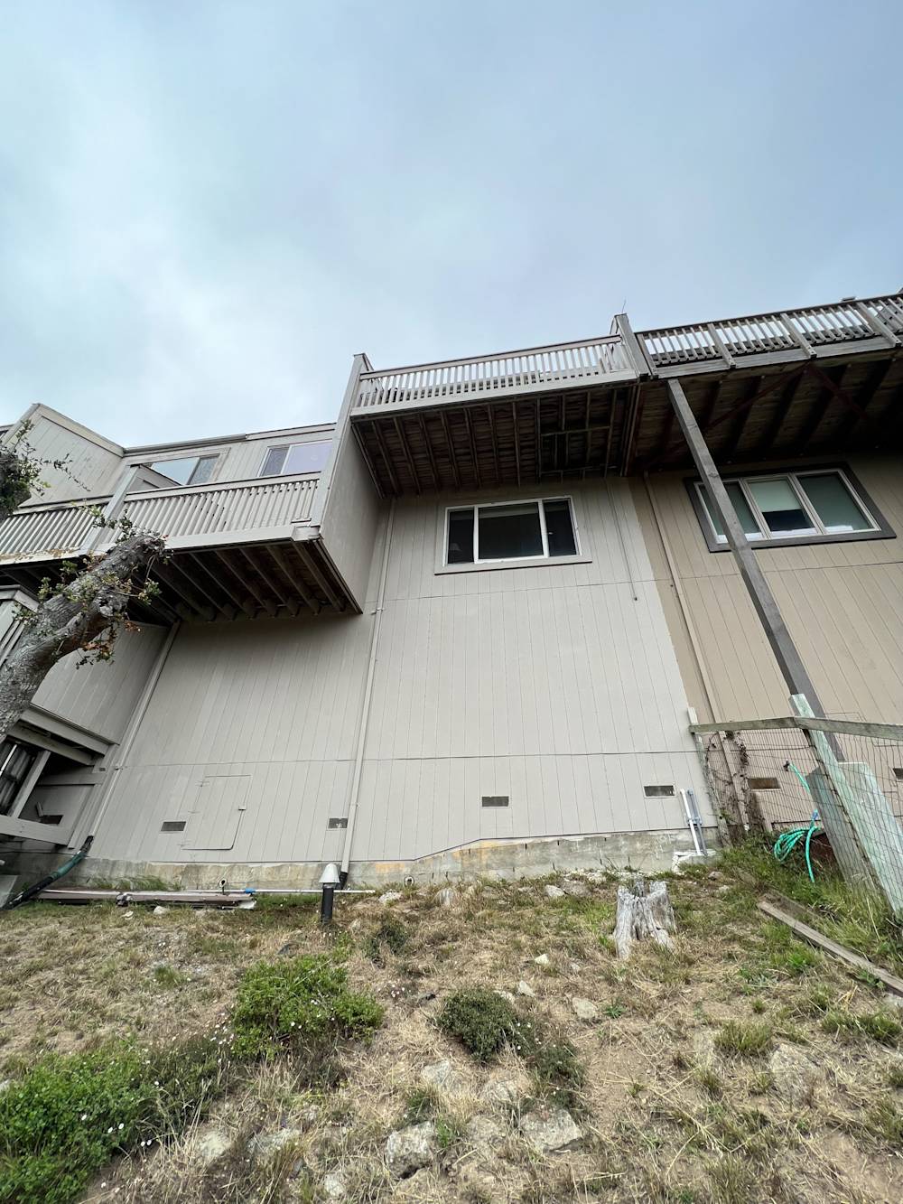 Exterior of a Sacramento home with wooden balconies and beige siding, showing a hillside landscape