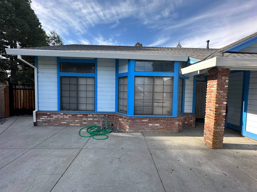 Light blue house exterior with large windows and red brick accents in Sacramento