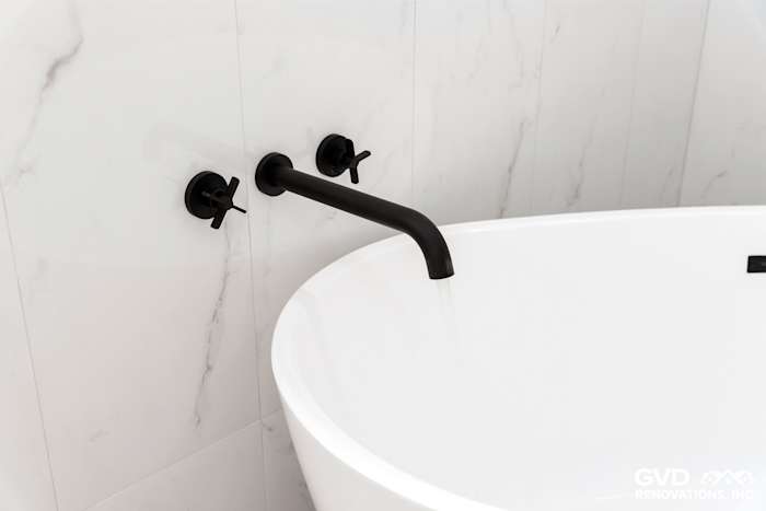 Modern bathroom featuring a freestanding tub with sleek black faucet and elegant marble wall tiles