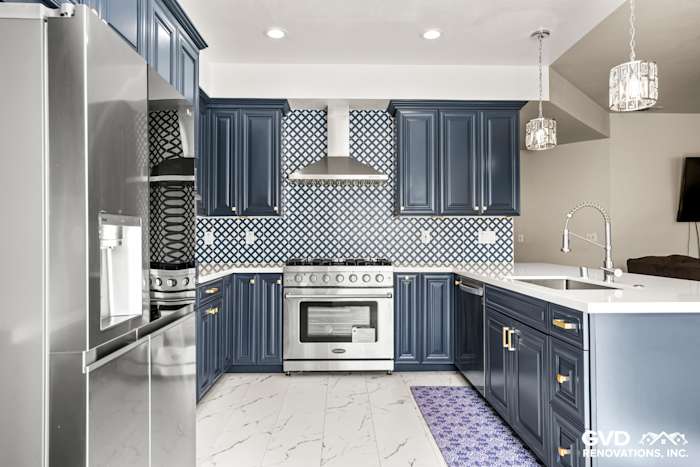 Navy blue cabinets and white quartz countertops in a remodeled Sacramento kitchen with decorative tile backsplash