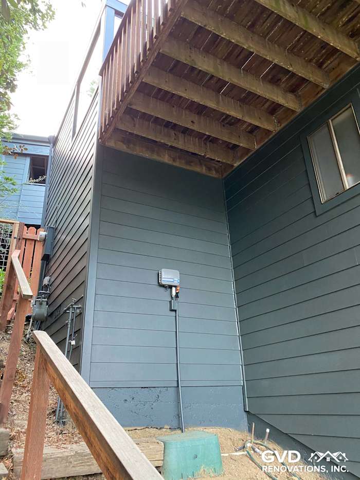 Newly installed James Hardie siding in dark gray on home's exterior, featuring a raised deck above