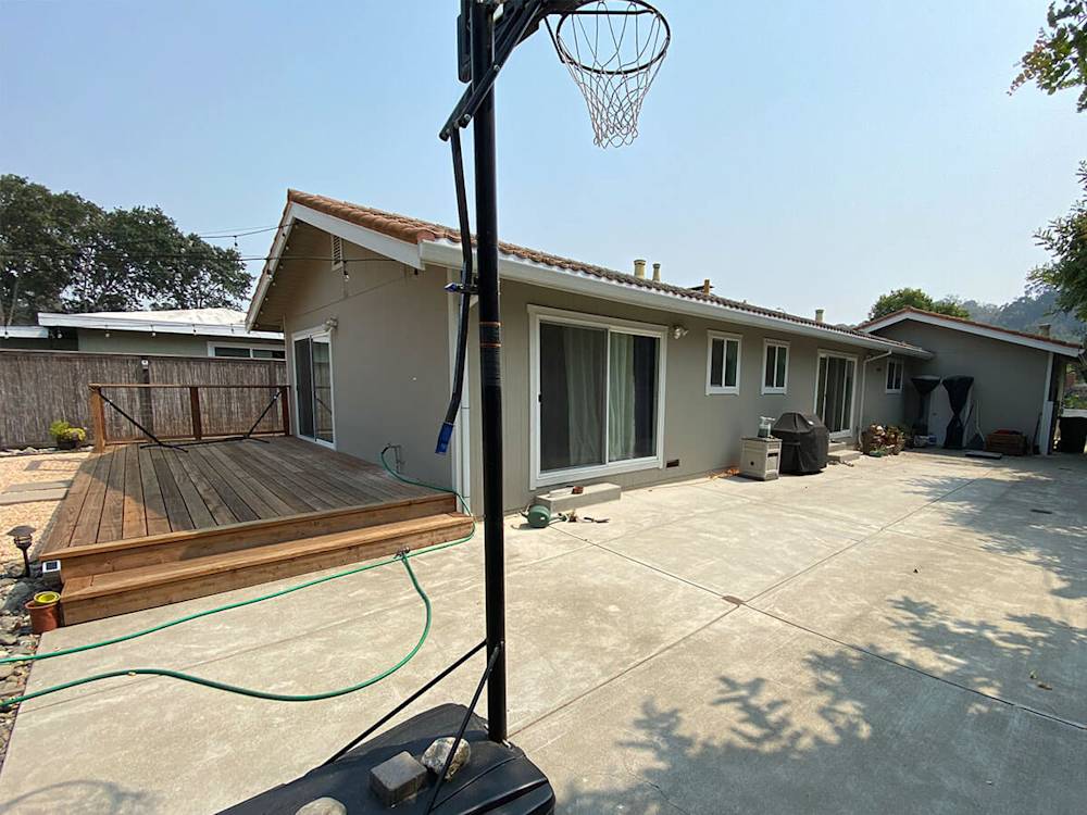 Dated exterior with beige paint, worn surfaces, and uninviting patio deck